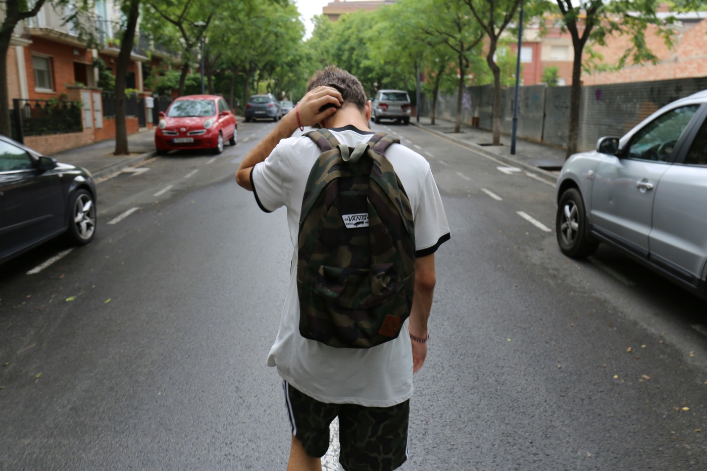Junger Mensch mit Rucksack geht eine Strasse entlang.