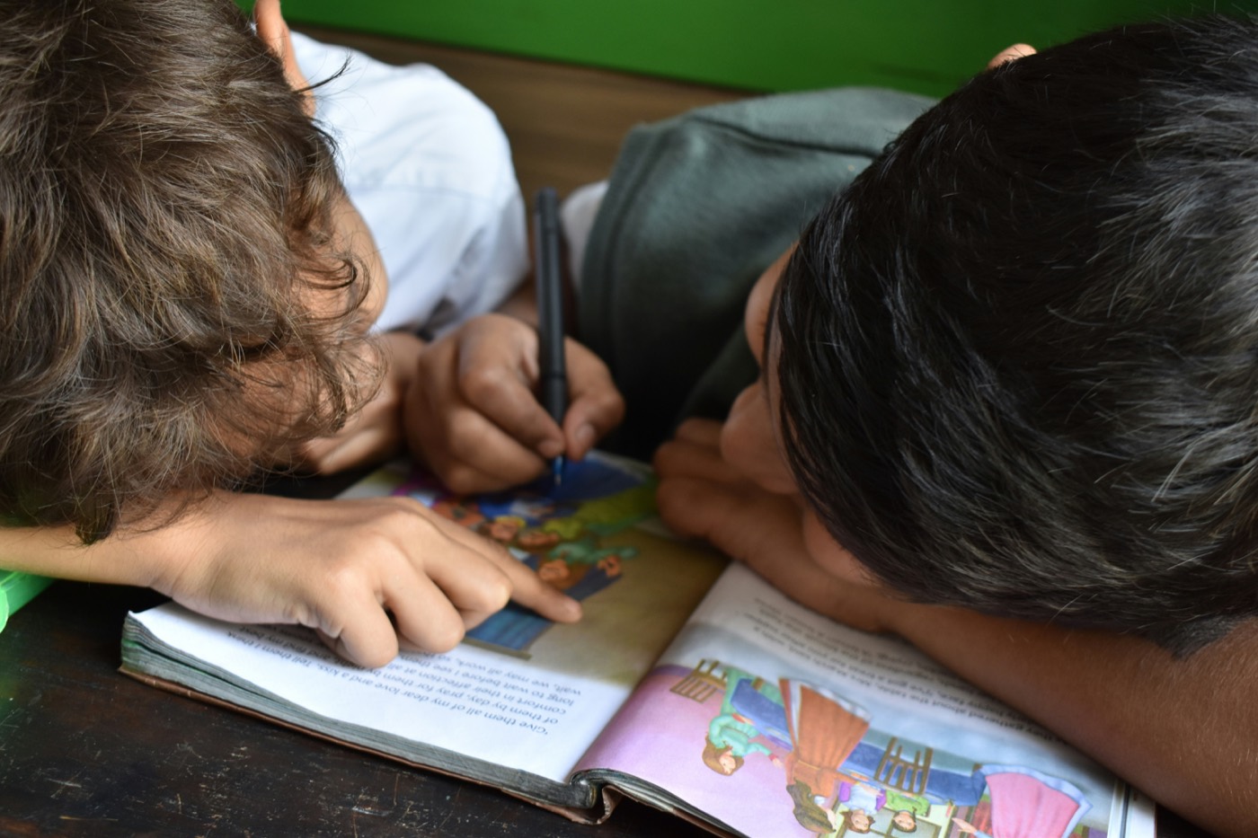 Zwei Kinder lesen und schreiben zusammen an einem Tisch.