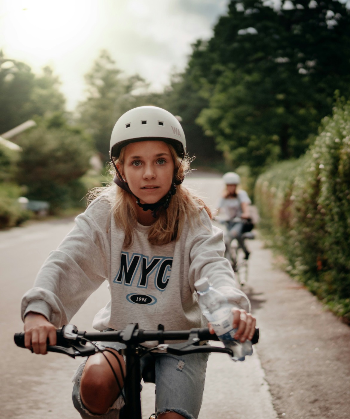 Jugendliche fährt auf einem Velo einen Weg entlang.